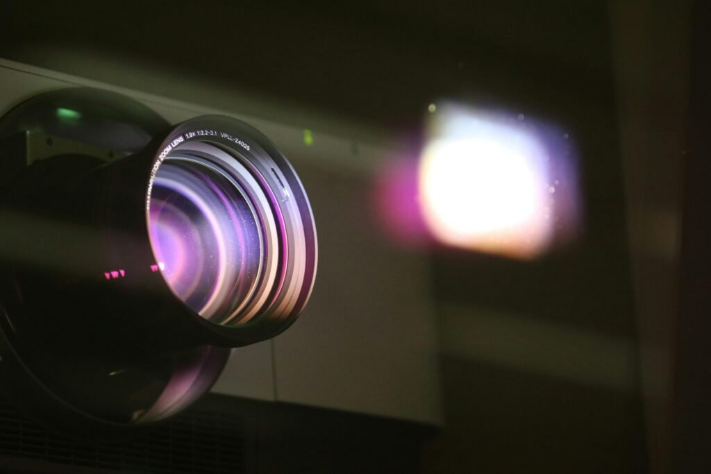 Close-up view of a projector lens with light reflections, highlighting optics and technology.